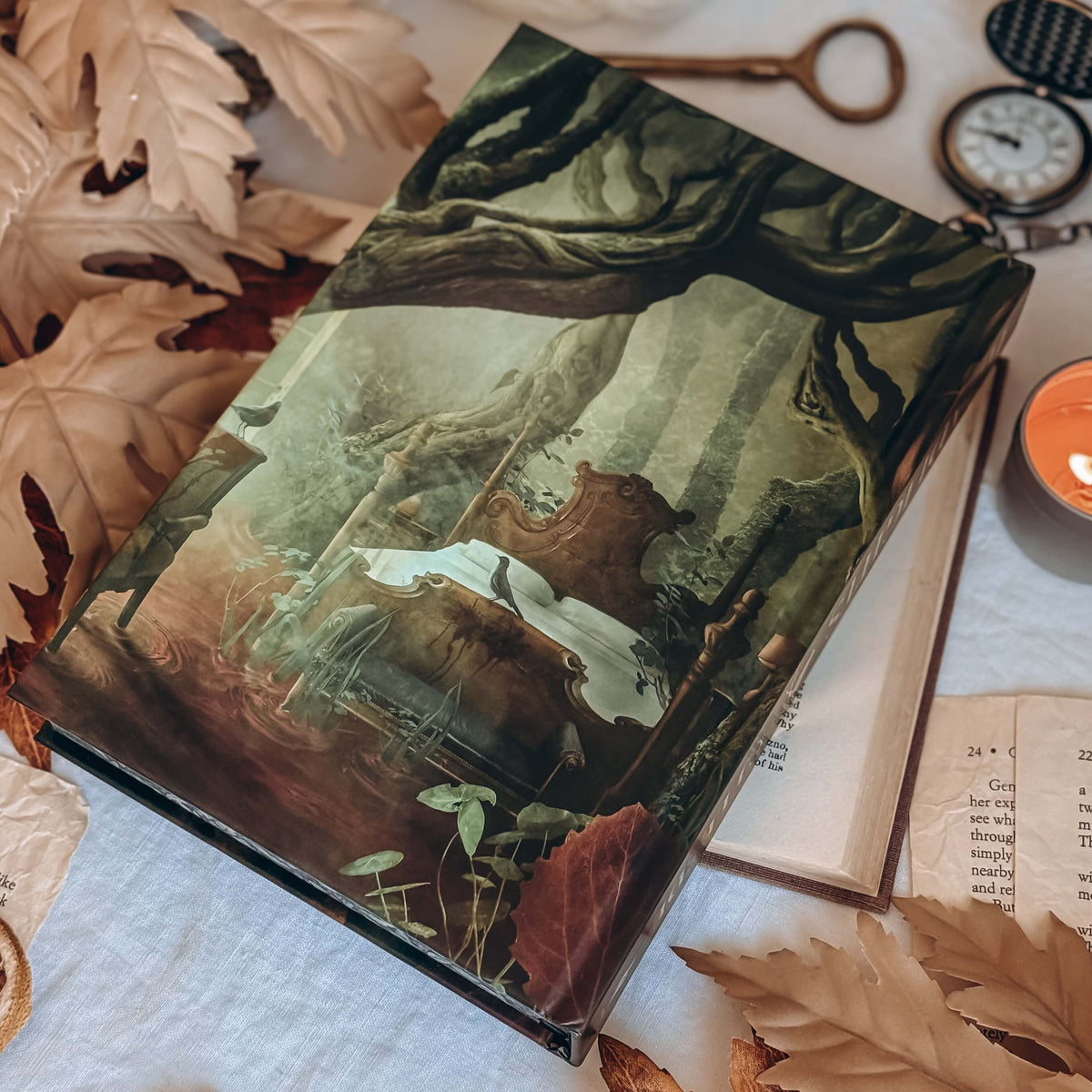 A hardcover book featuring an illustrated scene of a bed in an old, ancient, forest bog. The book is centered among various leaves, open books, an antique key, and a pocket watch.