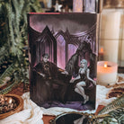 Reversible dust jacket for The Dark is Descending by Chloe C Peñaranda showing an illustration of two people sitting on their respective thrones in a dark, ornate setting. 