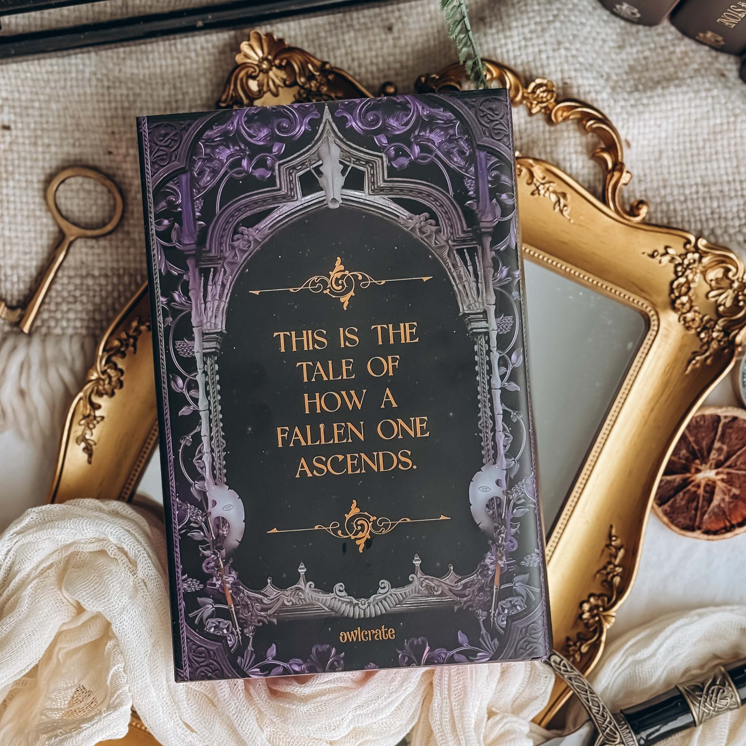 Back cover of The Fallen and the Kiss of Dusk by Carissa Broadbent showing  purple-tinted gothic architecture framing the text "This is the tale of how a fallen one ascends." 