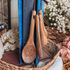 Six Crimson Cranes-inspired wooden measuring spoons held up by a book with blue sprayed edges.