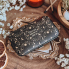 A black case with celestial designs and the quote There was only me to save me is centered, with baby's breath flowers, potpouri, and matchsticks surrounding.
